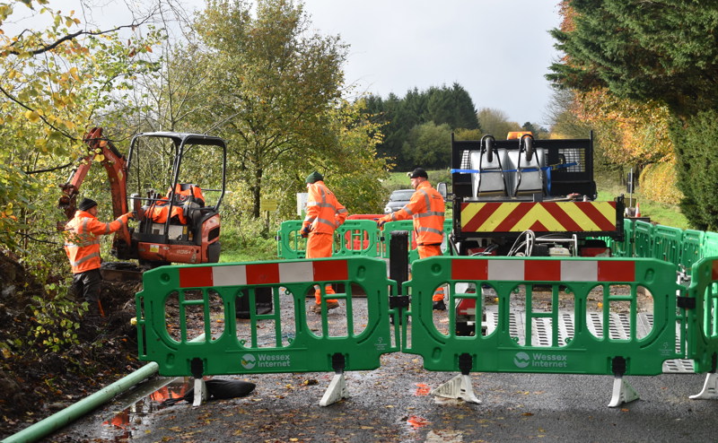 Male workers in high vis clothing and Wessex Internet branded barriers