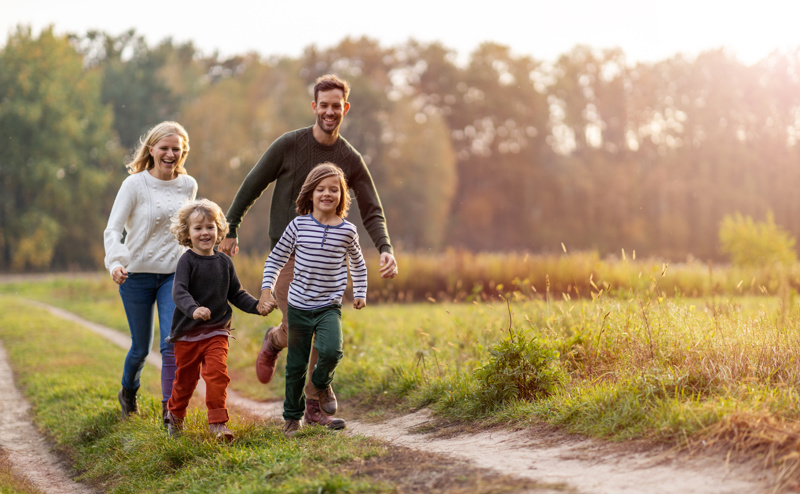 Family of four running through a field