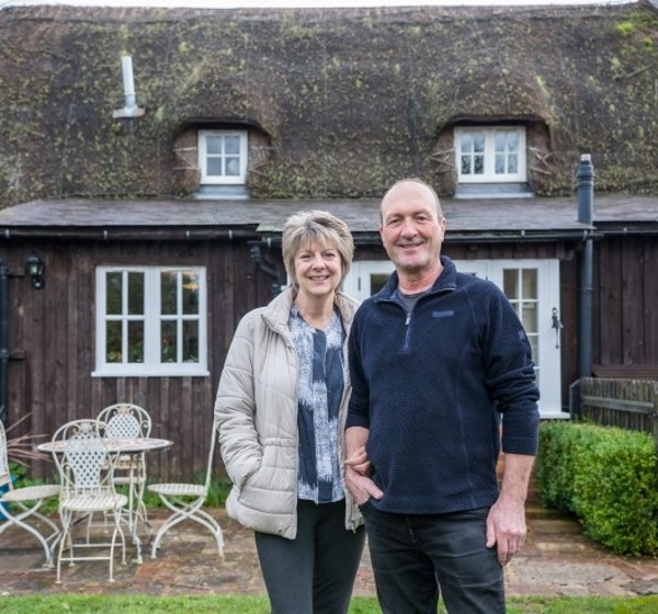 Gillian and Jeff Bailey in front of thatched cottage