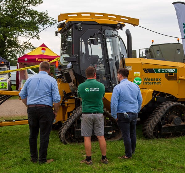 Three males stood looking at a mole plough