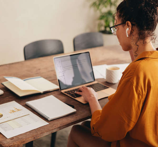A woman connected to her home broadband working at a dining table. 