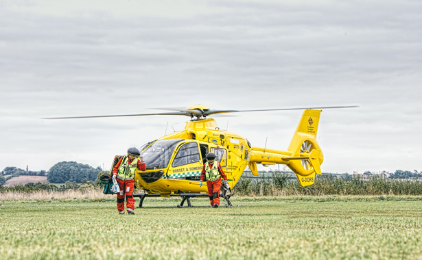 Two air ambulance crew members in front of the yellow helicopter